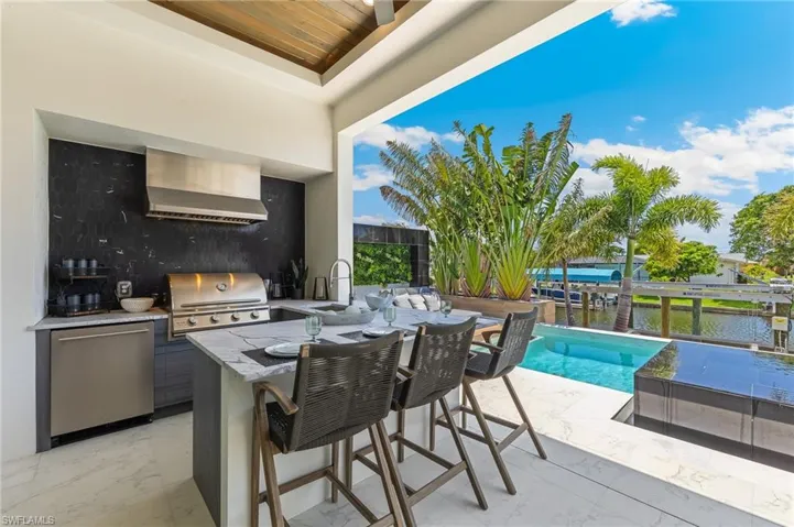 View of patio featuring a sink, a water view, and an outdoor pool