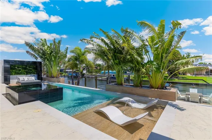 View of swimming pool featuring a water view, an outdoor living space, a pool with connected hot tub, and a patio