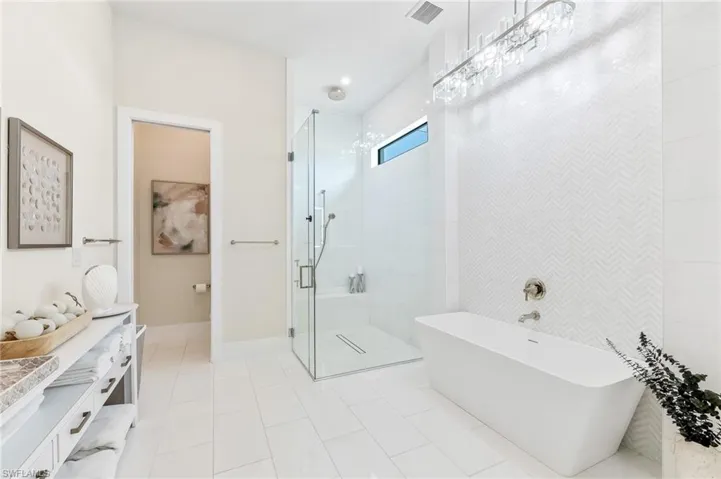 Bathroom with a shower stall, a soaking tub, vanity, tile patterned floors, and baseboards