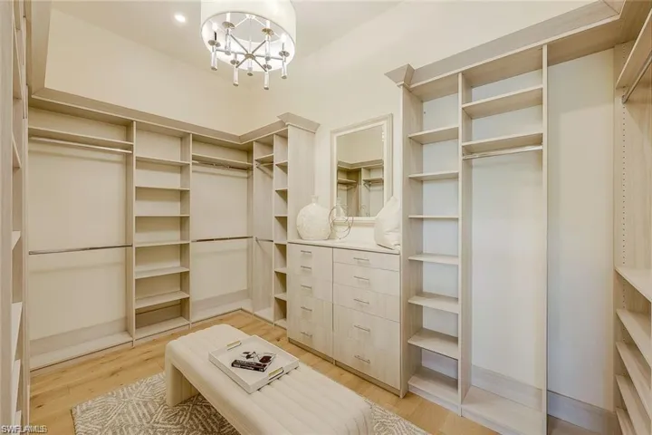 Spacious closet with light wood-style floors and a chandelier