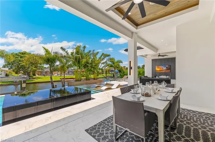 View of patio / terrace with a ceiling fan, a water view, outdoor dining area, and an infinity pool