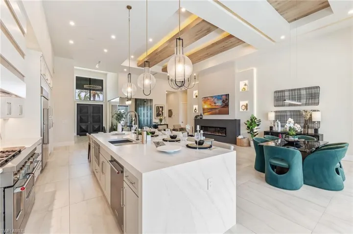 Kitchen featuring a sink, stainless steel dishwasher, a large island, open floor plan, and white cabinetry