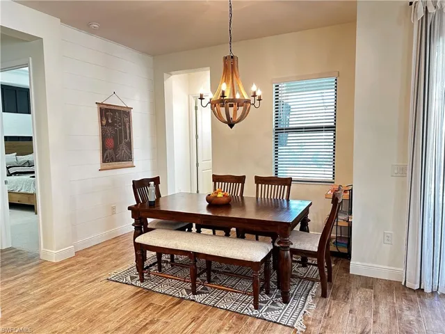 Dining space featuring an inviting chandelier, light wood-look tile flooring, and shiplap accent wall