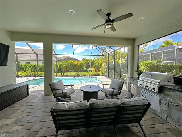 View of patio / terrace with an outdoor heated pool, an outdoor kitchen, area for grilling, roll down sun shades, and outdoor lounge area