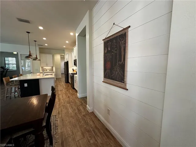 Dining room with recessed lighting, wood walls, visible vents, baseboards, and dark wood finished floors