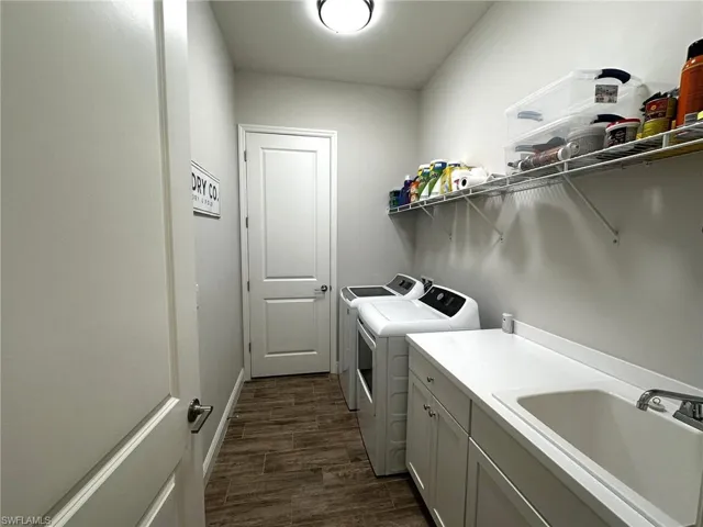 Laundry room featuring cabinets, dark hardwood / wood-look tile floors, sink, and washer and dryer