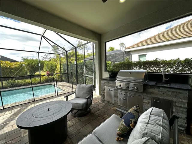 View of patio / terrace with an outdoor kitchen, a grill, sink, and roll-down shades