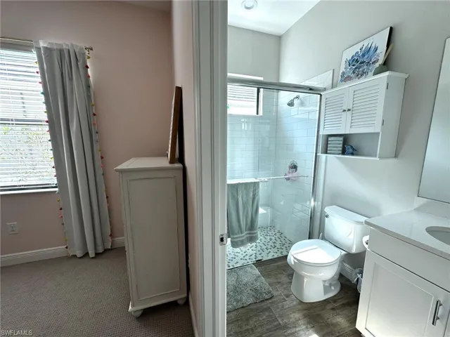 Ensuite Bathroom with vanity, a shower with shower door, and toilet
