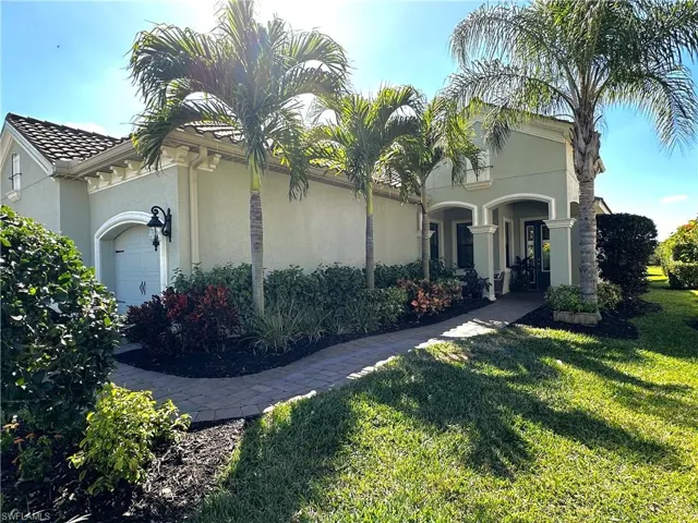 View of front of property featuring a garage, a front yard, a tile roof, and stucco siding