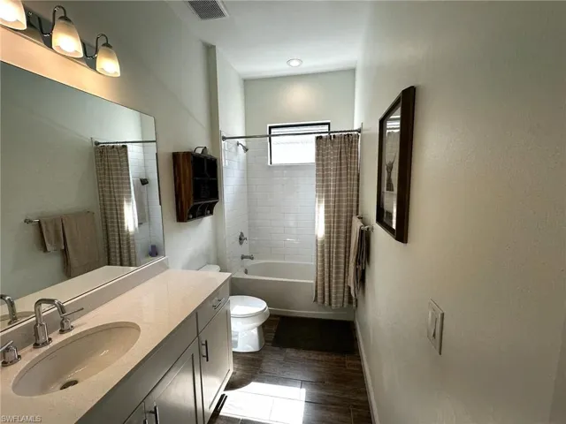 Full bathroom featuring wood-look tile flooring, vanity, toilet, and shower / tub combo