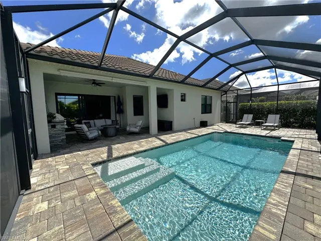 Pool with glass enclosure, an outdoor living space, a patio area, and a ceiling fan
