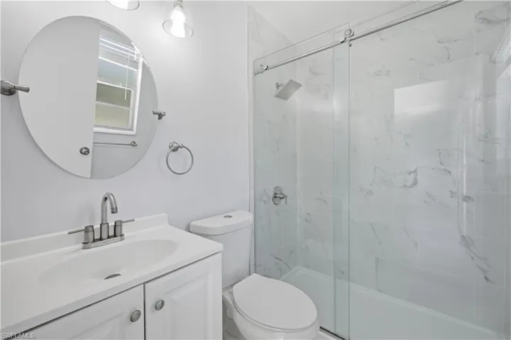 Bathroom featuring a white vanity with integrated sink, chrome faucet, and oval mirror