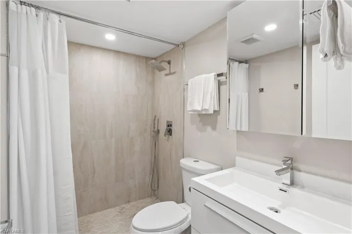 This updated guest bathroom boasts a sleek, modern vanity with a large, deep sink that adds both style and functionality to the space.