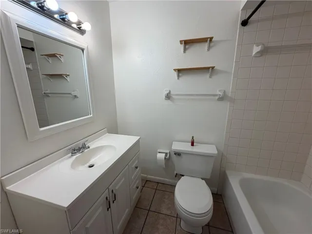 Full bath with vanity, light tile patterned floors, and bathtub / shower combination