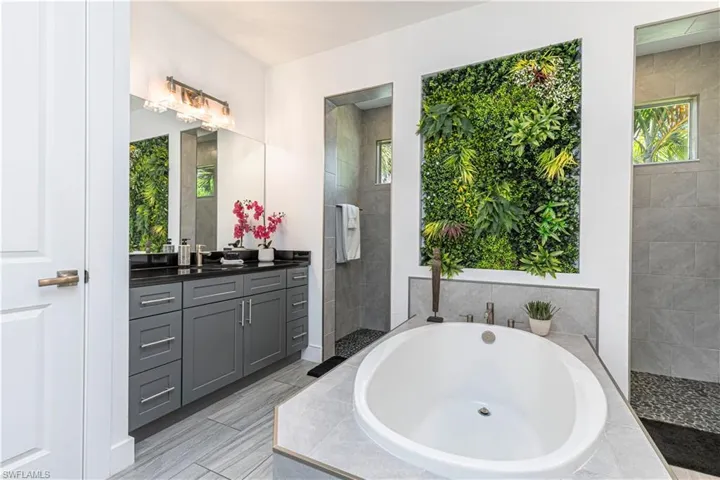 Bathroom with a bath, vanity, plenty of natural light, and a walk in shower