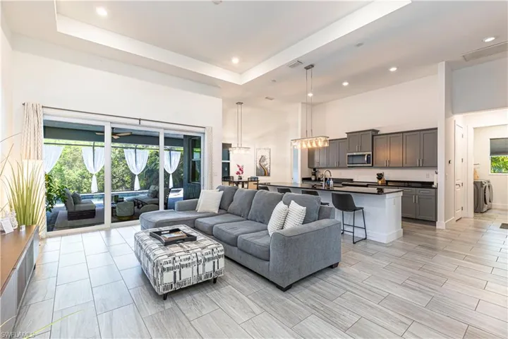 Living area featuring a towering ceiling, a tray ceiling, and recessed lighting