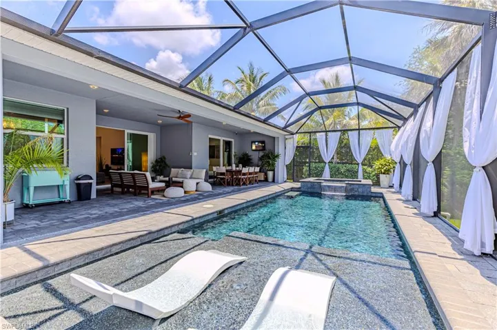 View of pool with an outdoor hangout area, a patio area, ceiling fan, and glass enclosure