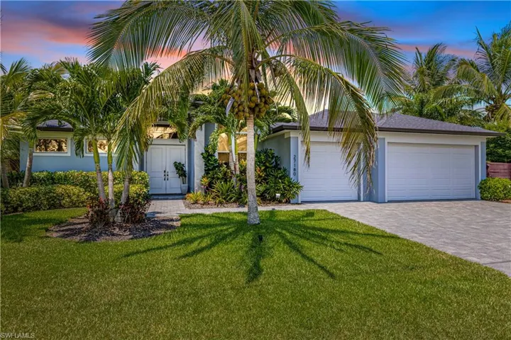 View of front of property with decorative driveway, a lawn, stucco siding, and a garage
