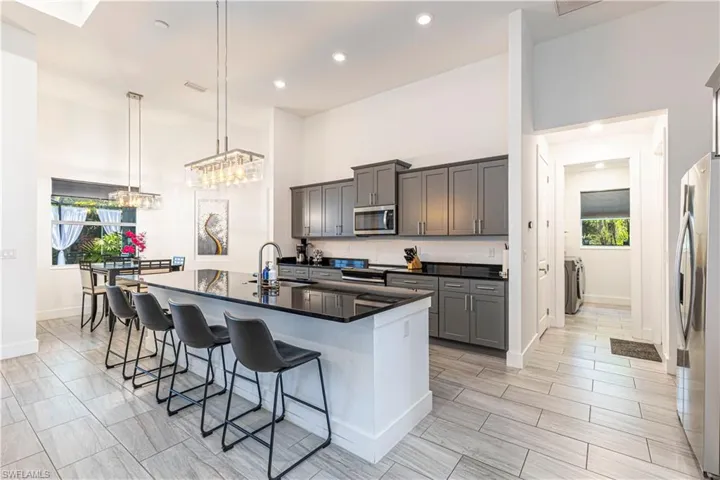 Kitchen with appliances with stainless steel finishes, a sink, dark countertops, a kitchen breakfast bar, and a kitchen island with sink