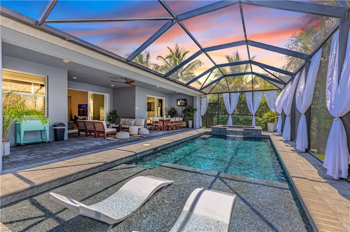 Pool at dusk with an outdoor living space, a patio, a ceiling fan, and a lanai