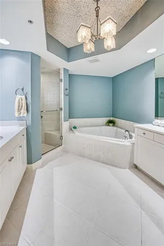 Bathroom with plus walk in shower, tile patterned floors, vanity, and a notable chandelier