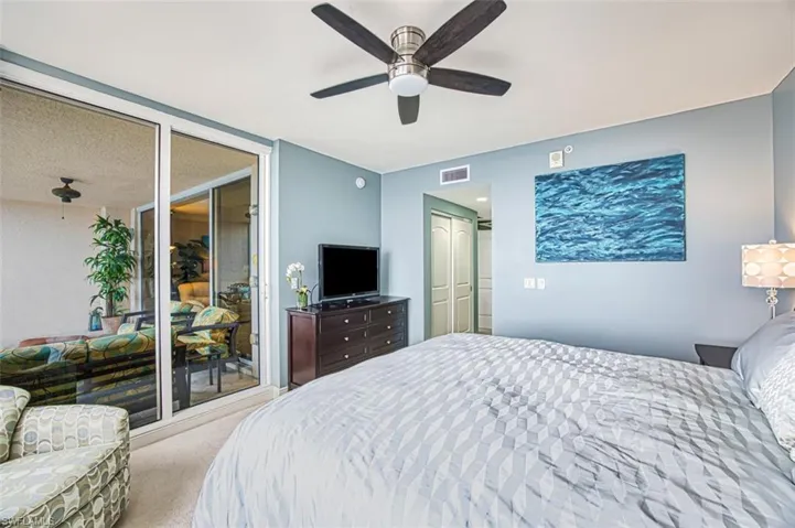 Carpeted bedroom with ceiling fan and multiple closets