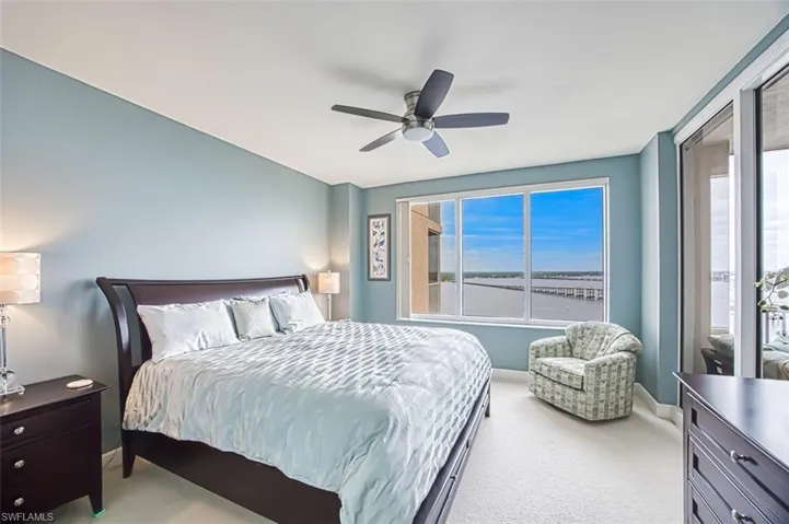 Carpeted bedroom featuring ceiling fan and a water view