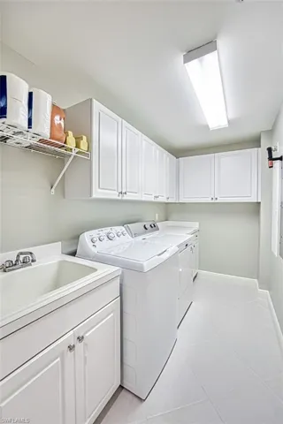Washroom with cabinets, sink, light tile patterned floors, and independent washer and dryer