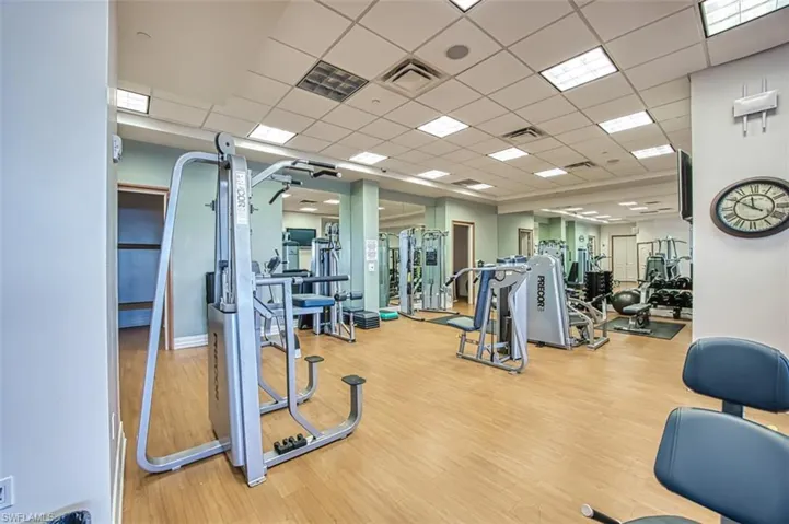 Workout area featuring light wood-type flooring and a drop ceiling