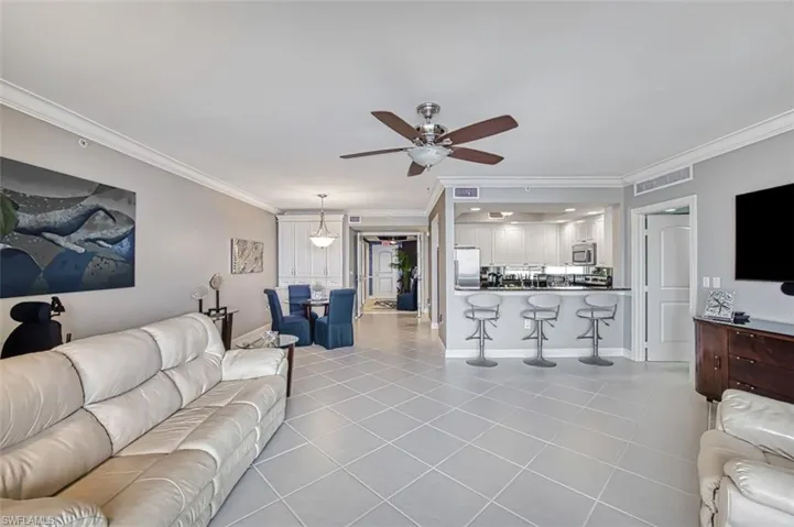 Living room featuring ceiling fan, light tile patterned flooring, and crown molding