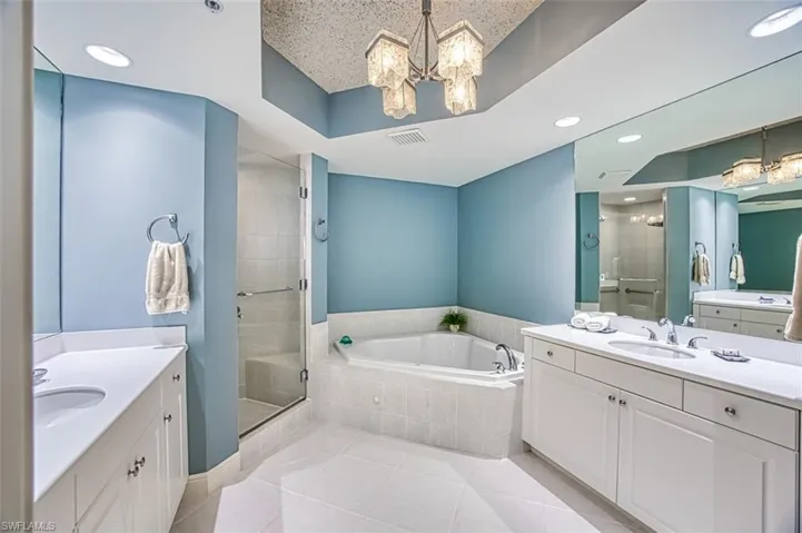 Bathroom with vanity, tile patterned floors, independent shower and bath, and a chandelier