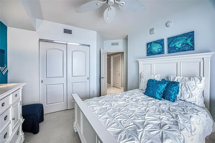 Carpeted bedroom featuring ceiling fan and a closet