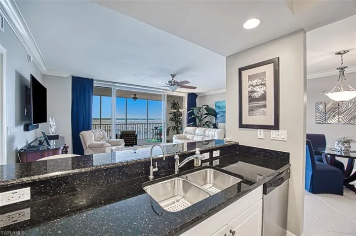Kitchen with white cabinetry, dark stone countertops, sink, light tile patterned flooring, and stainless steel dishwasher