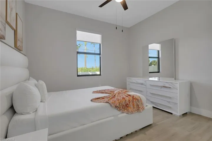 Bedroom with multiple windows, light wood finished floors, and a ceiling fan
