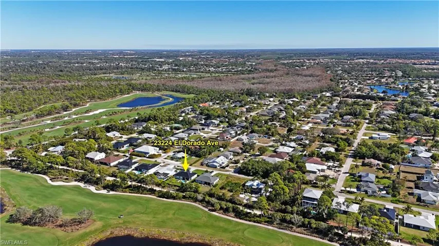 Aerial view of property and surrounding area featuring nearby suburban area, a large body of water, and a golf course