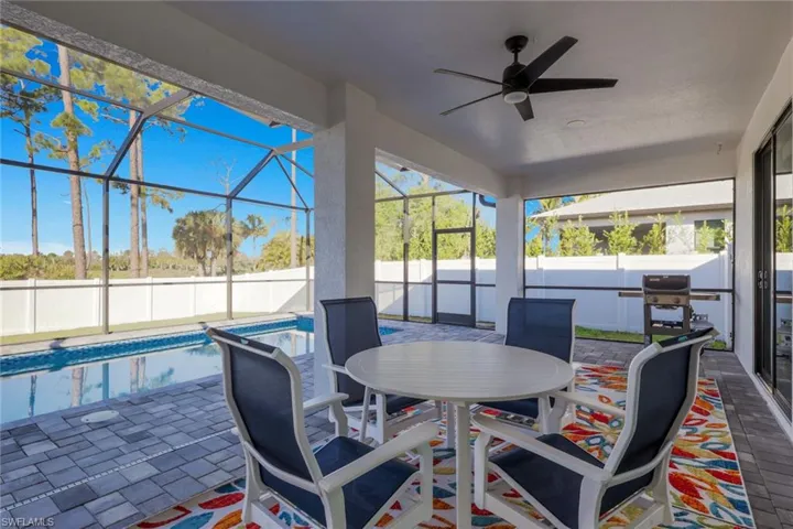 Fenced backyard featuring a patio area, glass enclosure, a sunroom, and a ceiling fan