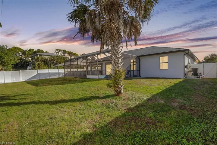 Back of property with a fenced backyard, a sunroom, glass enclosure, and stucco siding