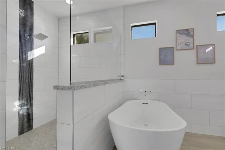Bathroom featuring a freestanding tub, walk in shower, and tile walls