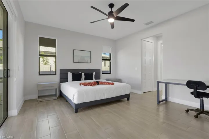 Bedroom featuring multiple windows, wood tiled floors, and ceiling fan