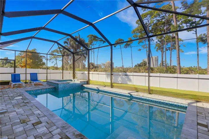 View of pool with a sunroom, a lanai, a fenced backyard, a pool with connected hot tub, and a patio area