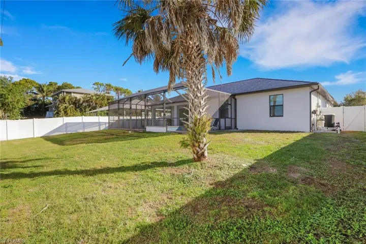 Back of property with a fenced backyard, a sunroom, a lanai, and stucco siding