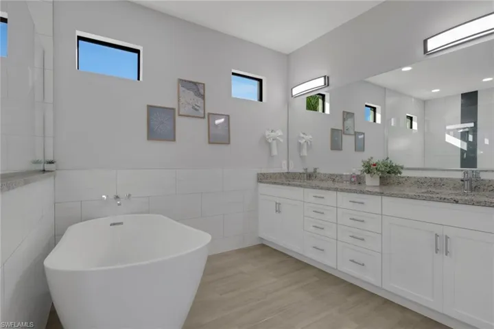 Full bathroom with double vanity, a soaking tub, healthy amount of natural light, tile walls, and a tile shower