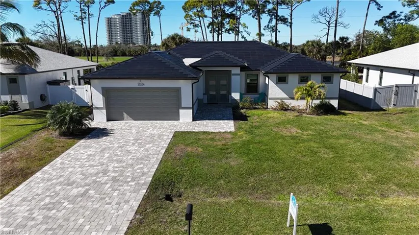 View of front of property featuring decorative driveway, an attached garage, stucco siding, a gate, and french doors
