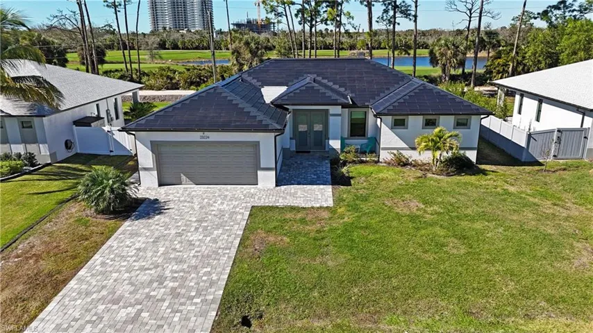 View of front of property featuring decorative driveway, an attached garage, stucco siding, a water view, and a gate