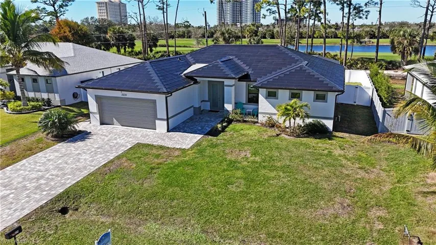 View of front of house featuring a garage, stucco siding, decorative driveway, and a water view