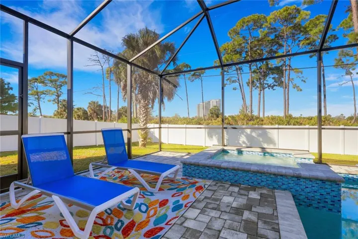 Fenced backyard featuring a lanai, an in-ground hot tub, and a sunroom