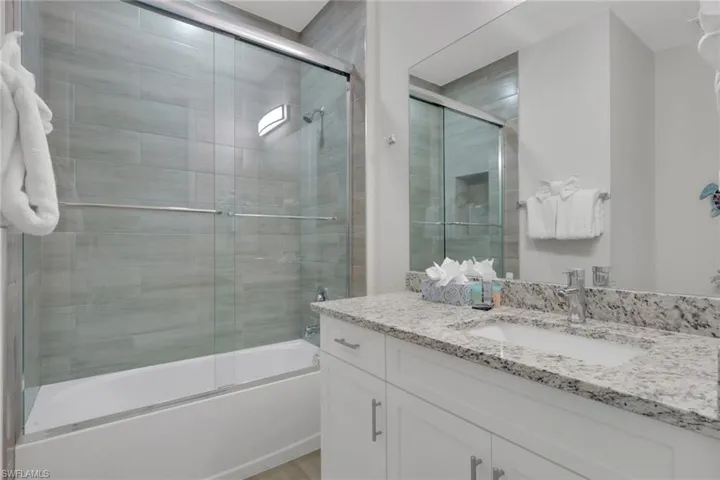 Full bathroom with enclosed tub / shower combo and vanity