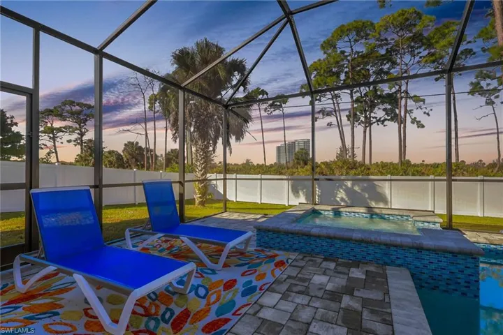 Patio terrace at dusk with a sunroom, an in-ground hot tub, and glass enclosure