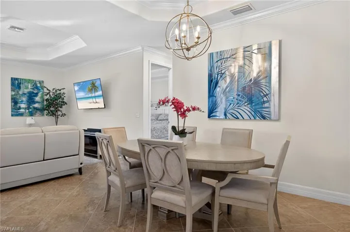 Dining area with ornamental molding, a chandelier, and a tray ceiling