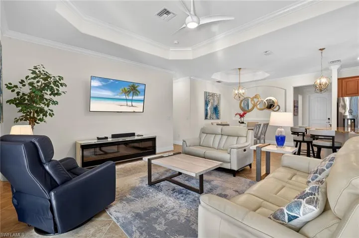 Living area featuring ceiling fan, crown molding, a tray ceiling, and suspended lighting